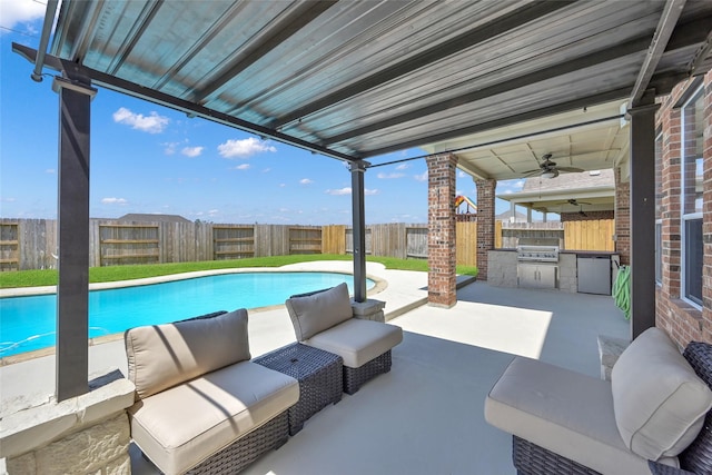 view of pool featuring ceiling fan, area for grilling, a patio area, and exterior kitchen