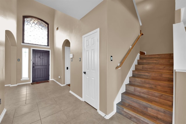 entryway with light tile patterned flooring and a high ceiling