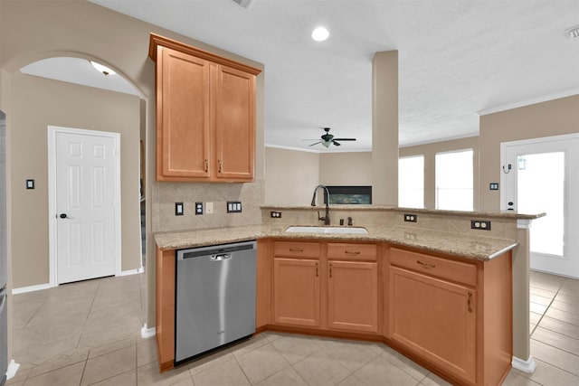 kitchen featuring dishwasher, backsplash, sink, ceiling fan, and light stone counters