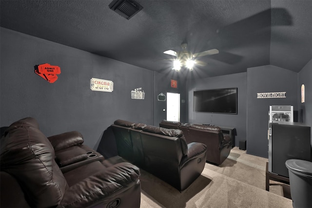 cinema with lofted ceiling, a textured ceiling, and light carpet