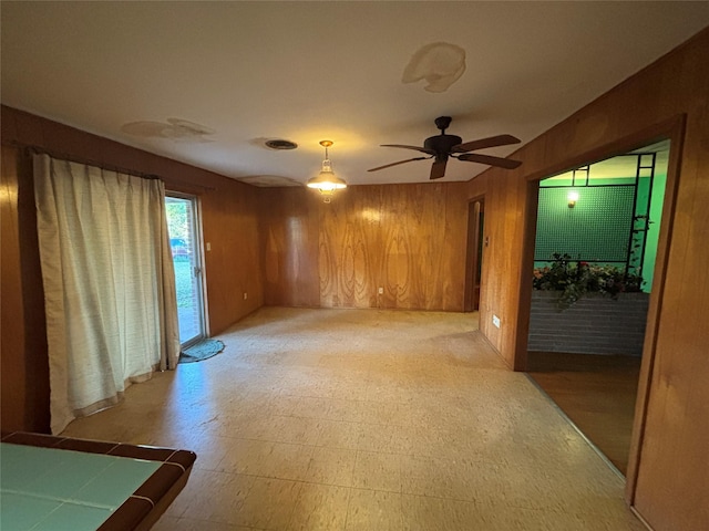 unfurnished room featuring ceiling fan and wooden walls