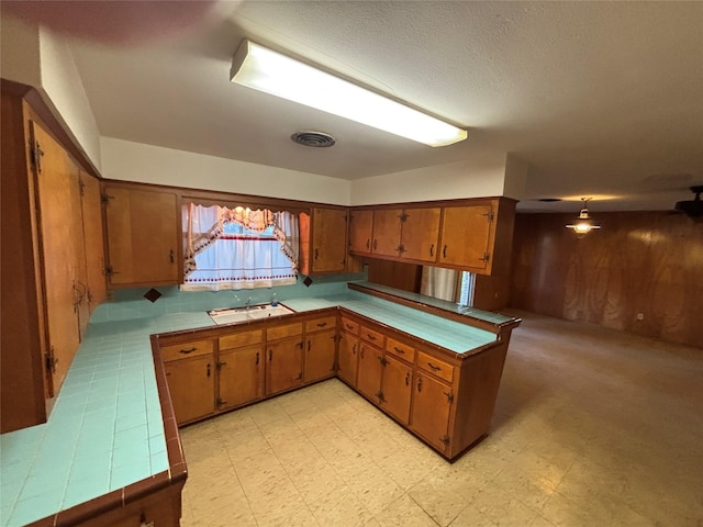 6402 Jim St, Houston, TX 77092 - kitchen featuring brown cabinetry, a peninsula, tile countertops, and light flooring