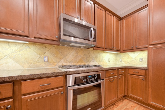 kitchen featuring crown molding, light wood-type flooring, stainless steel appliances, and tasteful backsplash