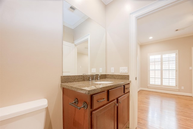 bathroom featuring wood-type flooring, vanity, toilet, and ornamental molding