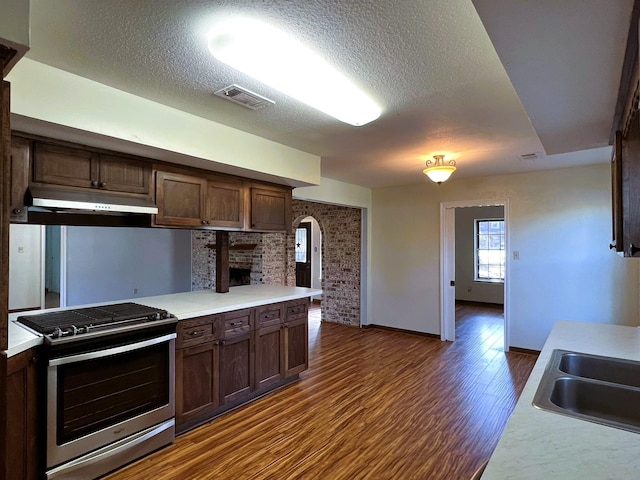 kitchen featuring a textured ceiling, dark brown cabinets, stainless steel stove, and dark hardwood / wood-style floors