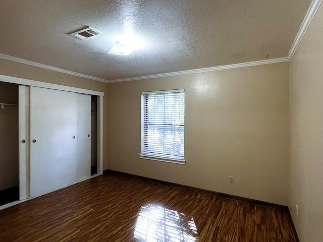 unfurnished bedroom with crown molding, a closet, dark wood-type flooring, and a textured ceiling