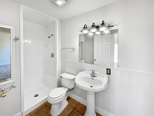 bathroom featuring tile patterned flooring, toilet, tile walls, and walk in shower