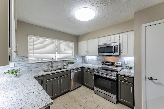 kitchen with gray cabinetry, sink, light tile patterned floors, appliances with stainless steel finishes, and white cabinetry