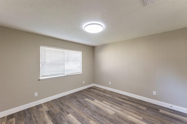 empty room featuring dark hardwood / wood-style flooring and a textured ceiling