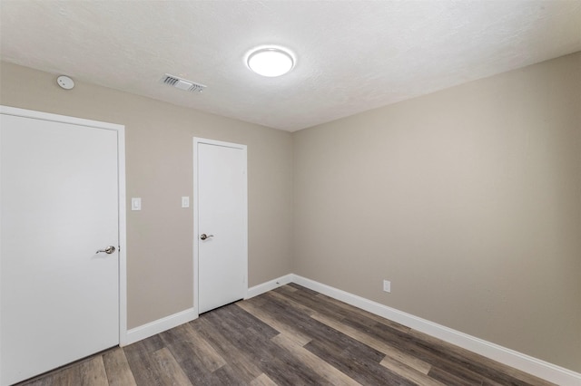 spare room with dark hardwood / wood-style flooring and a textured ceiling