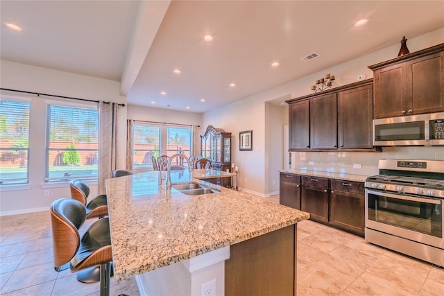 kitchen with a center island with sink, a kitchen breakfast bar, sink, and stainless steel appliances