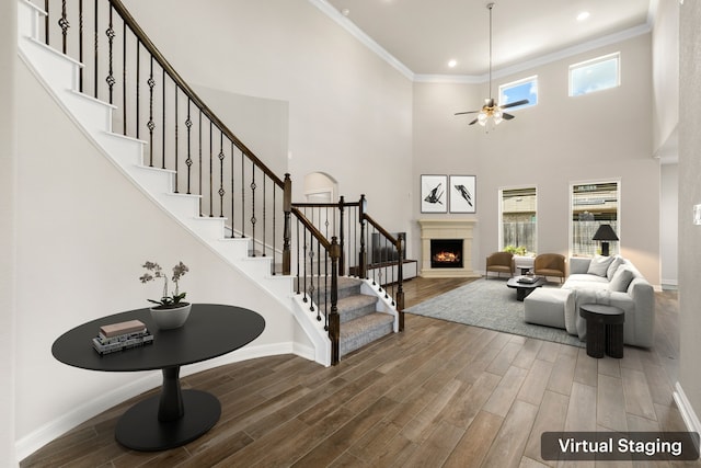 foyer with ceiling fan, ornamental molding, and a towering ceiling