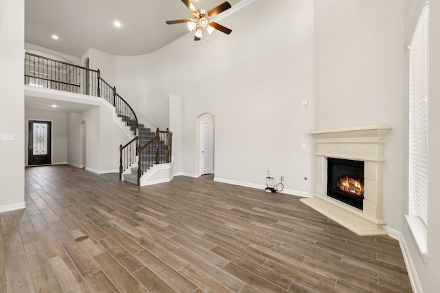 unfurnished living room with ceiling fan, dark wood-type flooring, and a high ceiling