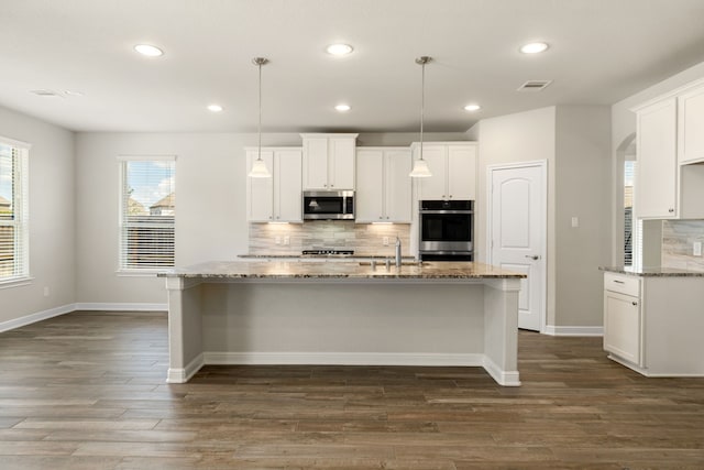 kitchen with backsplash, white cabinetry, hanging light fixtures, and appliances with stainless steel finishes