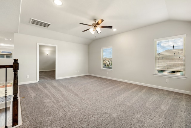 empty room with carpet floors, vaulted ceiling, a wealth of natural light, and ceiling fan