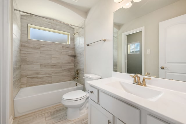 full bathroom featuring vanity, tiled shower / bath combo, and toilet