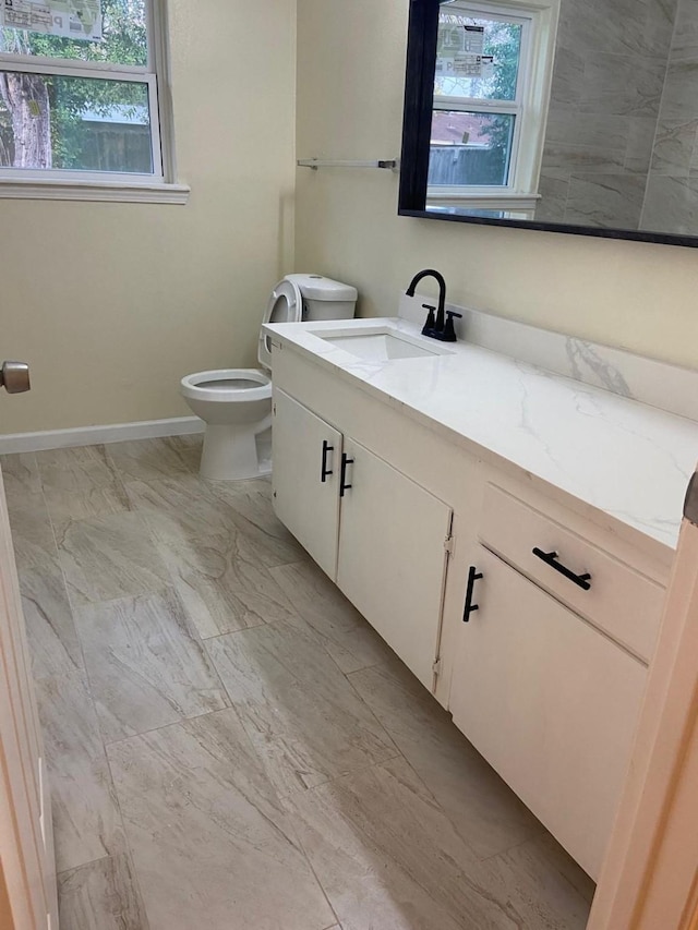 bathroom with vanity, toilet, and a healthy amount of sunlight