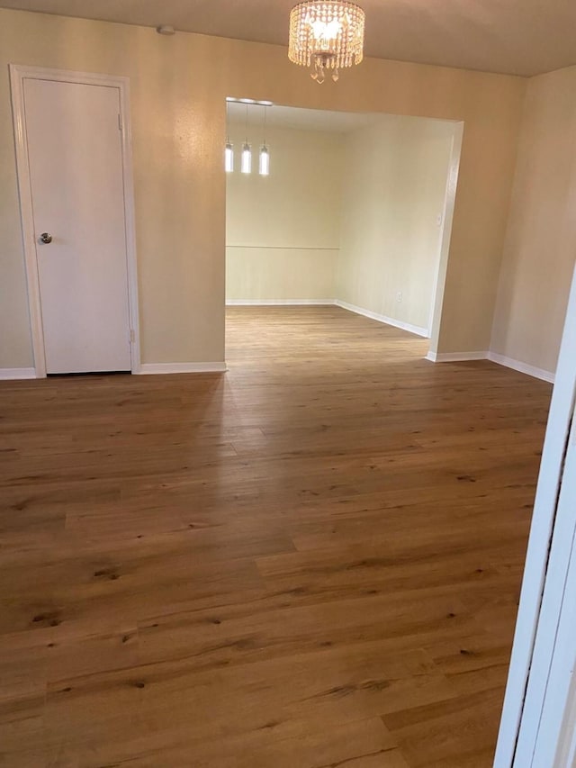 empty room featuring a chandelier and wood-type flooring