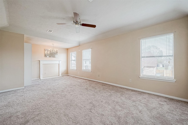 unfurnished living room with ceiling fan with notable chandelier, carpet floors, and a textured ceiling