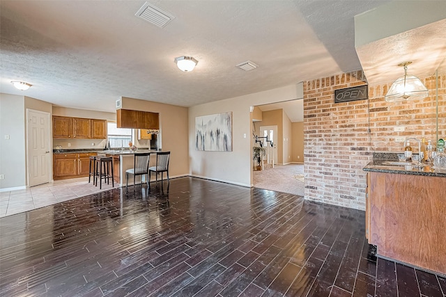 kitchen with a textured ceiling, a breakfast bar, sink, and decorative light fixtures