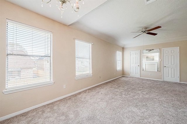 spare room featuring carpet, a textured ceiling, and ceiling fan with notable chandelier