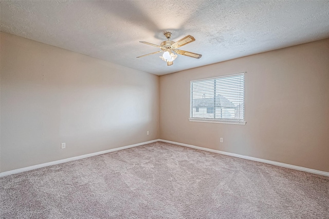 empty room with ceiling fan, light colored carpet, and a textured ceiling