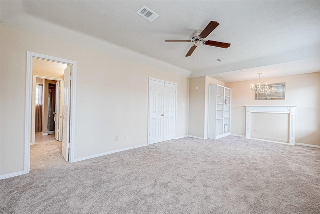 unfurnished living room with a textured ceiling, light colored carpet, and ceiling fan with notable chandelier