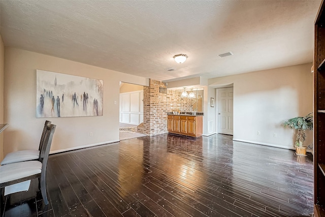 unfurnished living room with dark hardwood / wood-style flooring and a textured ceiling