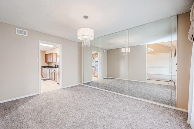 interior space with light carpet, connected bathroom, a closet, and a notable chandelier