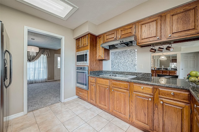 kitchen with light carpet, stainless steel appliances, and dark stone countertops