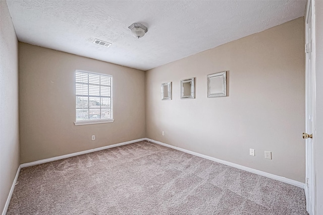 spare room with a textured ceiling and light colored carpet