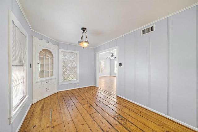 unfurnished dining area with ceiling fan, light hardwood / wood-style floors, and crown molding