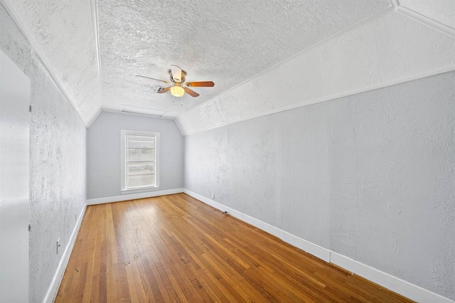 additional living space with hardwood / wood-style floors, a textured ceiling, ceiling fan, and lofted ceiling