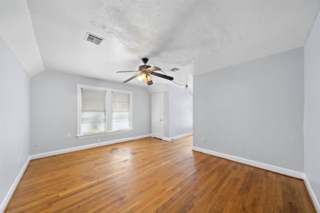 empty room featuring hardwood / wood-style floors, ceiling fan, a textured ceiling, and vaulted ceiling