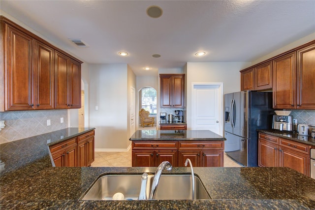 kitchen featuring backsplash, dark stone counters, and sink