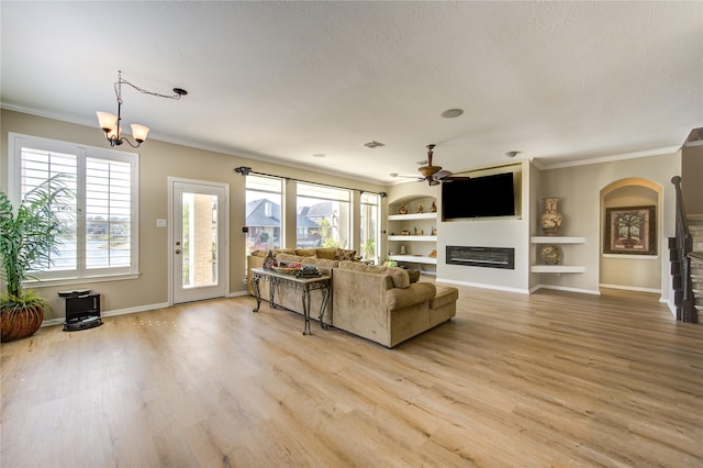 living room with ceiling fan with notable chandelier, light hardwood / wood-style flooring, built in features, and ornamental molding