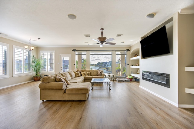 living room with built in shelves, crown molding, and light hardwood / wood-style floors