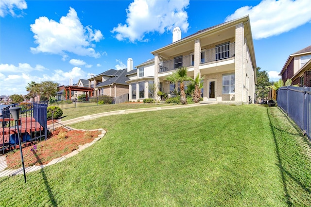 back of house with a balcony and a lawn