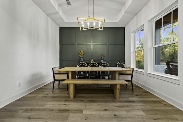 dining space featuring hardwood / wood-style flooring and a tray ceiling