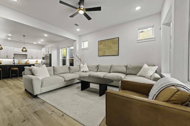 living room featuring a wealth of natural light, ceiling fan, light hardwood / wood-style flooring, and sink