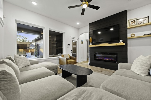 living room featuring ceiling fan, a fireplace, and light hardwood / wood-style floors