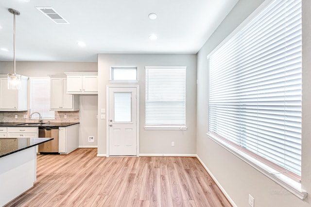 kitchen with light wood-type flooring, backsplash, decorative light fixtures, dishwasher, and white cabinets