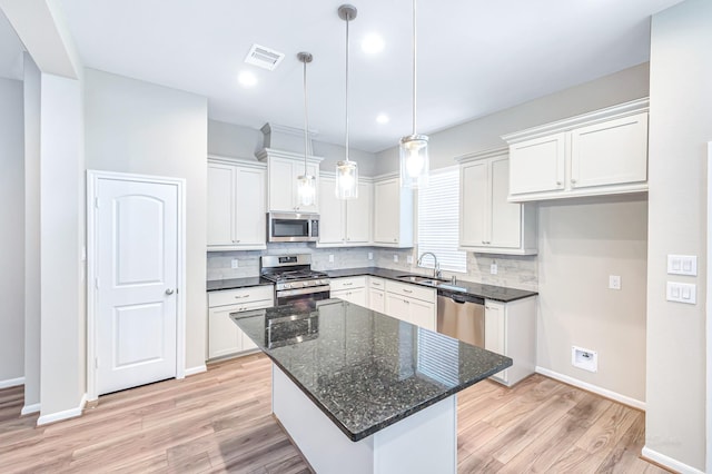 kitchen featuring white cabinetry, sink, a center island, stainless steel appliances, and tasteful backsplash