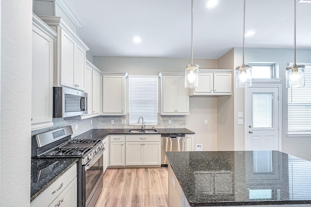 kitchen featuring backsplash, sink, stainless steel appliances, and decorative light fixtures