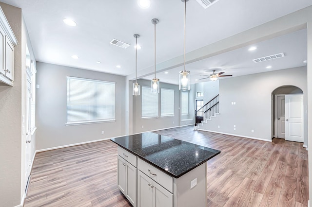 kitchen with dark stone counters, ceiling fan, light wood-type flooring, decorative light fixtures, and white cabinetry