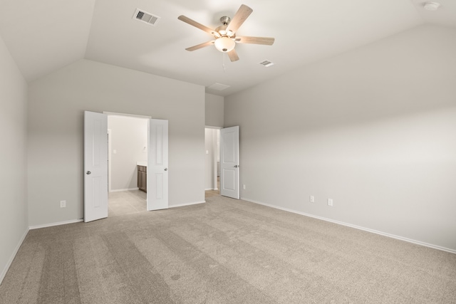 unfurnished bedroom featuring ceiling fan, ensuite bath, light carpet, and vaulted ceiling