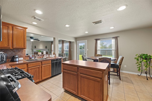 kitchen featuring decorative backsplash, a textured ceiling, sink, black dishwasher, and light tile patterned flooring