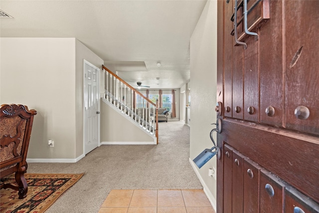 entryway with ceiling fan and light carpet