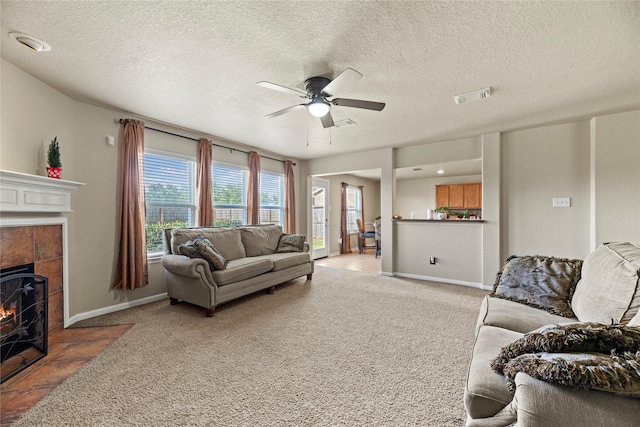 living room with a fireplace, light carpet, a textured ceiling, and ceiling fan