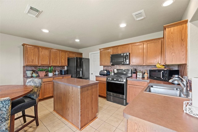 kitchen with sink, a center island, backsplash, light tile patterned floors, and black appliances